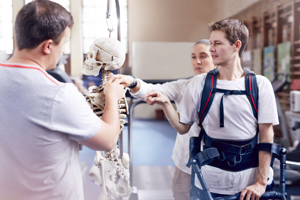 Physical therapist explaining spine model to man