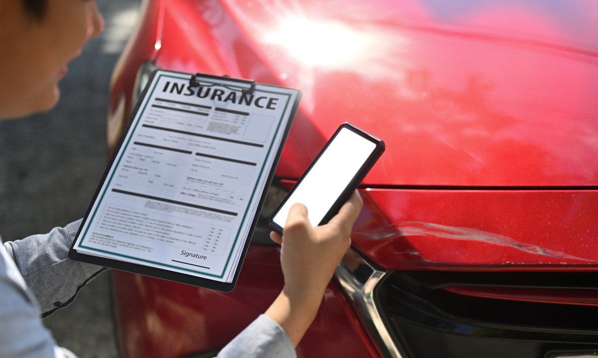 Insurance adjuster reviewing a claim form during a vehicle inspection